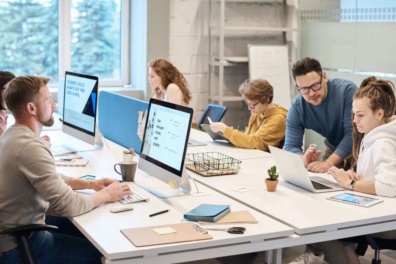 L'equip treballant a l'oficina, entre pantalles i escriptoris compartits